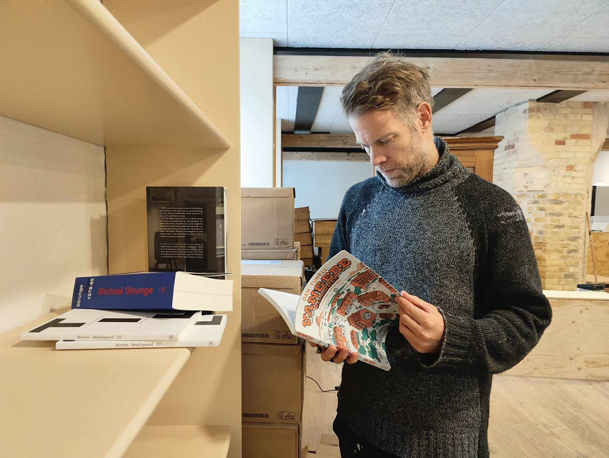 Claus Nivaa står med Dan Turèlls "Vangede billeder", Café Ordgeist, Aalborg, før åbningen.