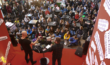 Kenneth Bøgh Andersen i samtale med Jacob Skou Bæk i Kedelhallen i Nordkraft. Foran scenen sidder og står en masse unge mennesker